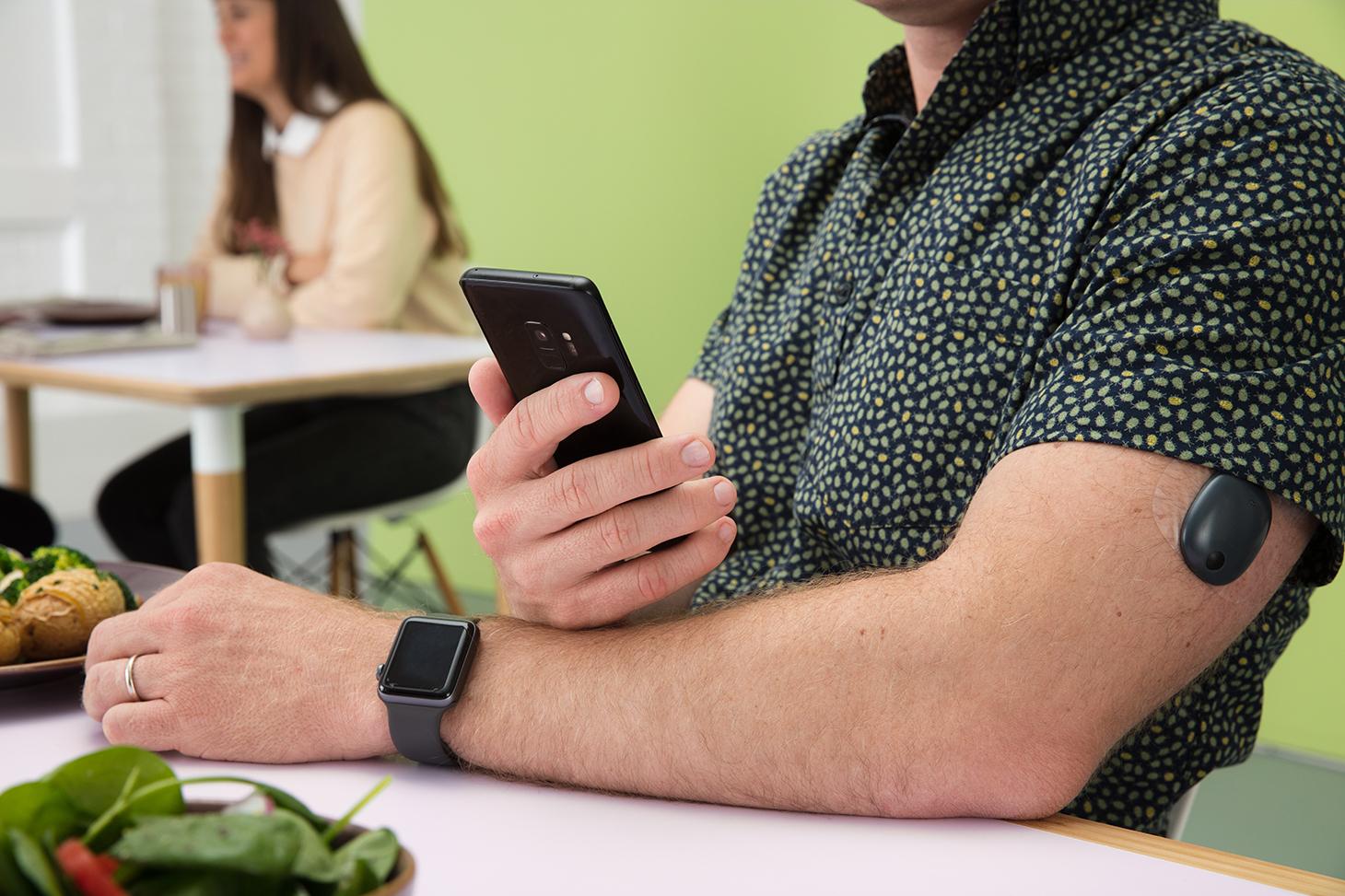 Man sitting on a table with an Eversense CGM on his arm