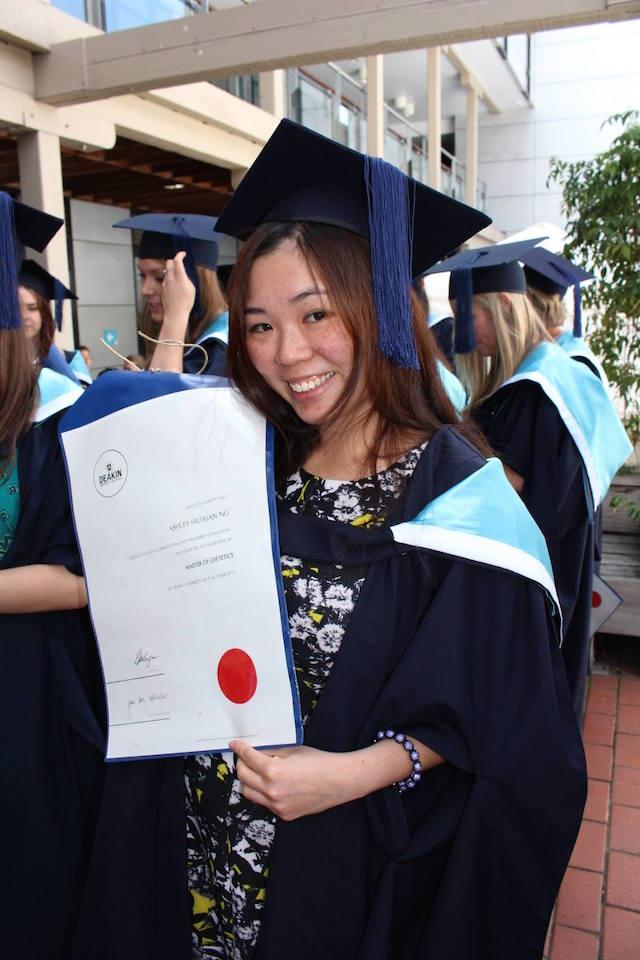 Ashley holding her diploma and in her graduation gown