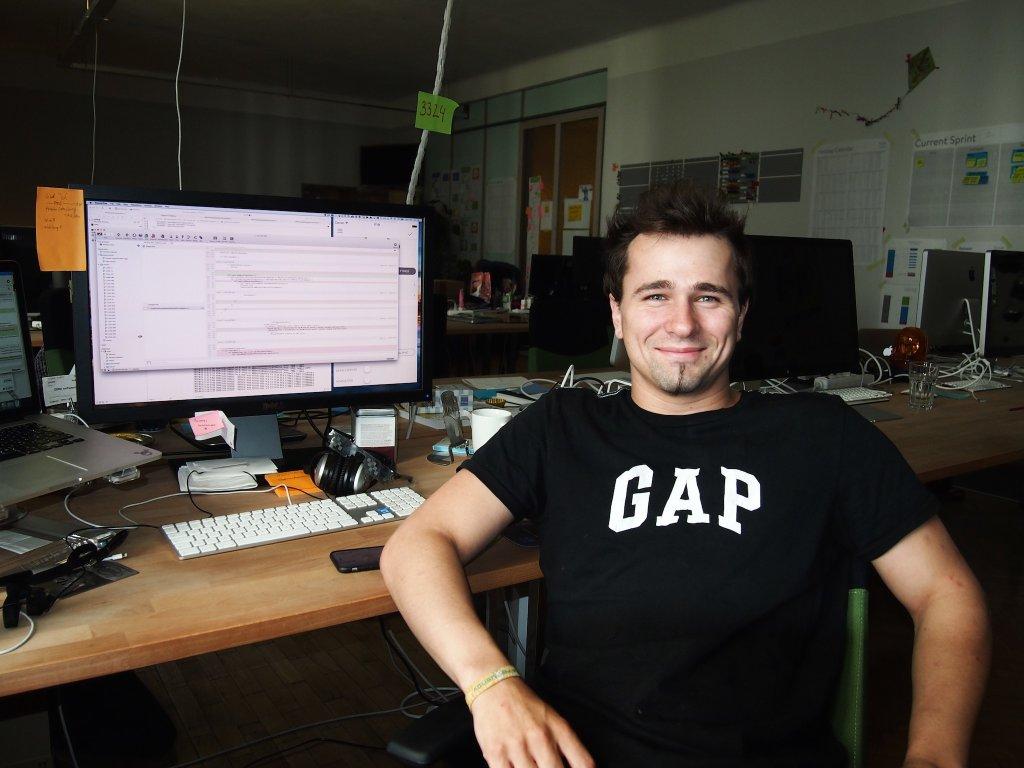 Lukas at his desk smiling at the camera